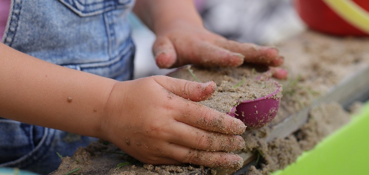 Kindergartenkind beim Spielen mit Matsch und Förmchen Kindergartenkind beim Spielen mit Matsch und Förmchen