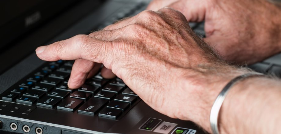 Seniorenhände auf Computertastatur