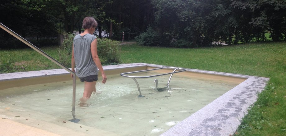 Frau beim Kneippen im Wassertretbecken