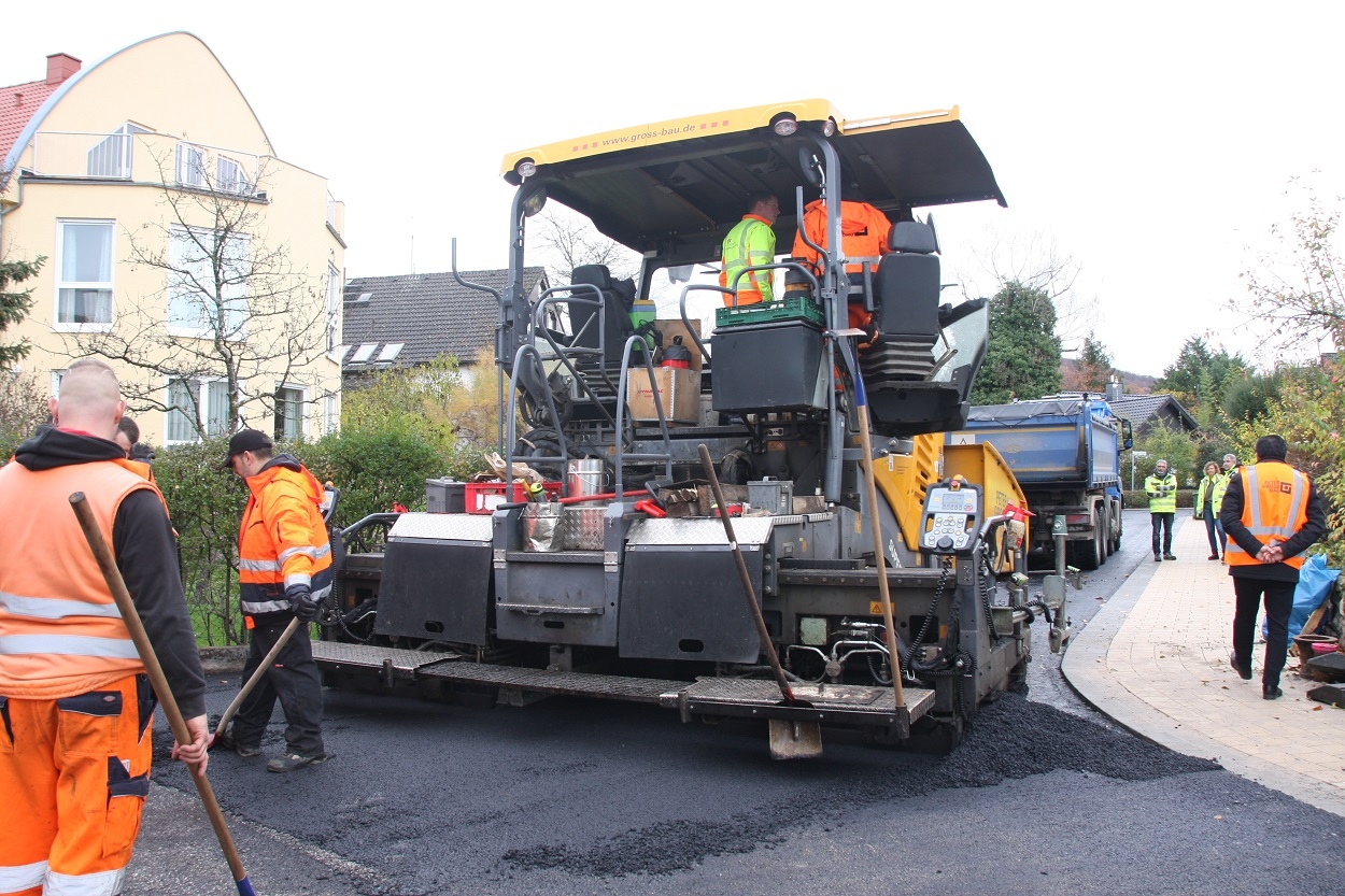 Straßensanierung Straßensanierung mit Walze und Bauarbeitern im Vordergrund