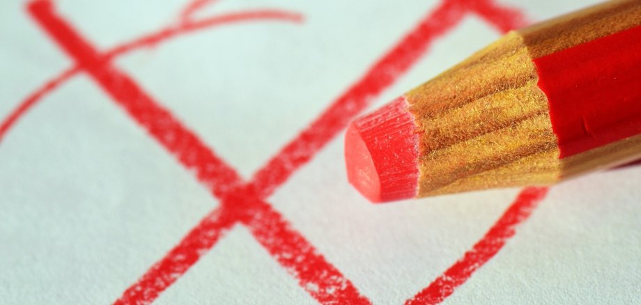 roter Stift mit Wahlkreuz auf einem Stimmzettel