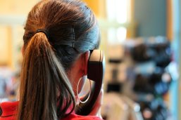 Frau mit Telefonhörer am Ohr bei Telefonieren